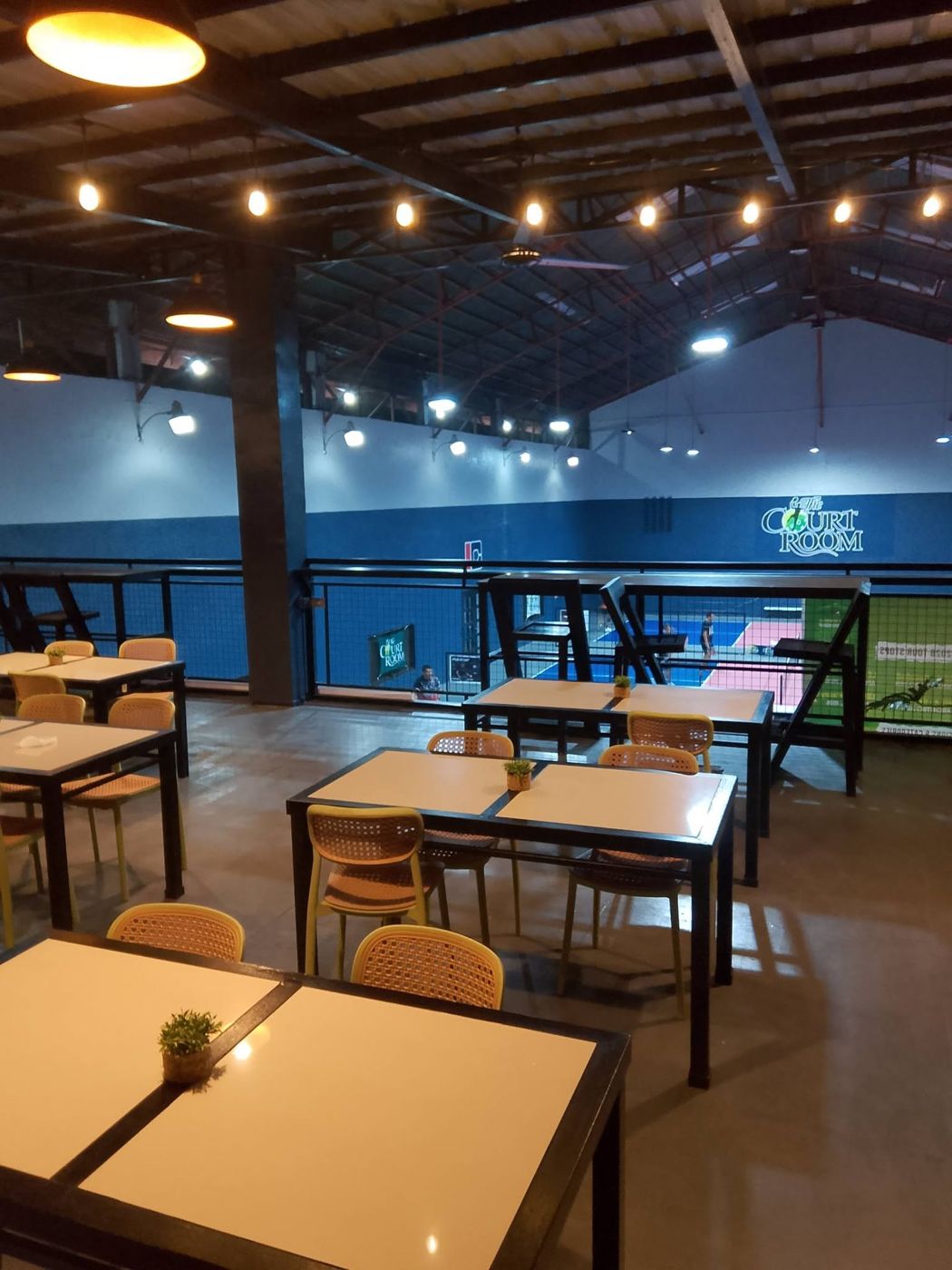 Upper deck tables overlooking the lit pickleball courts